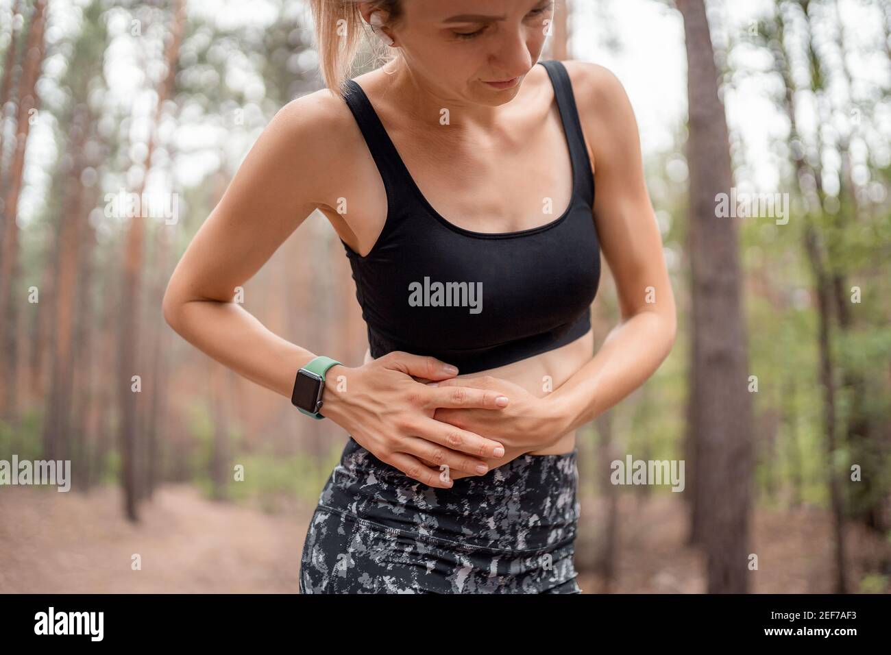 Side stitch woman runner side cramps after running. Jogging woman with stomach side pain after