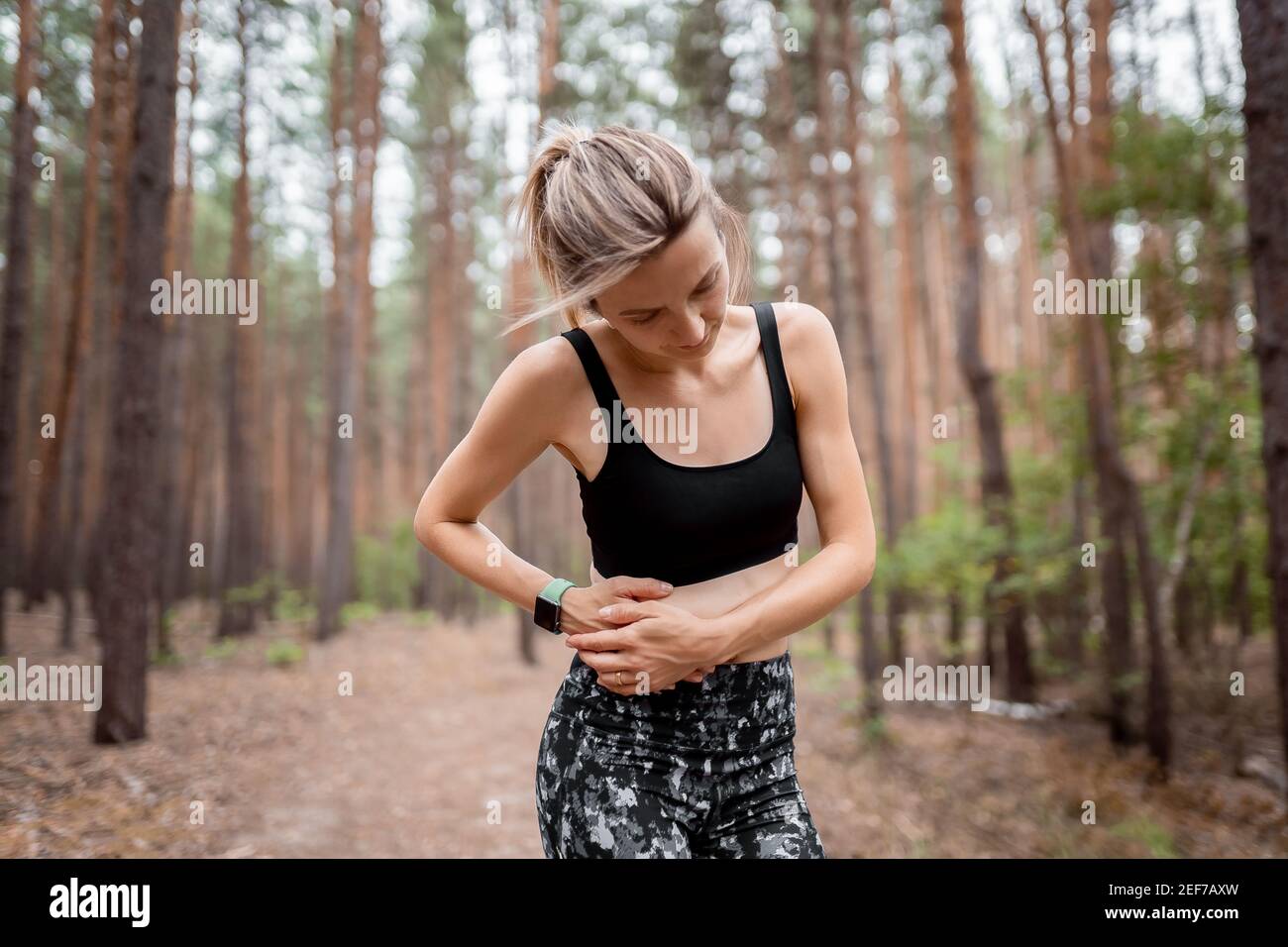 Side stitch woman runner side cramps after running. Jogging woman with stomach side pain after