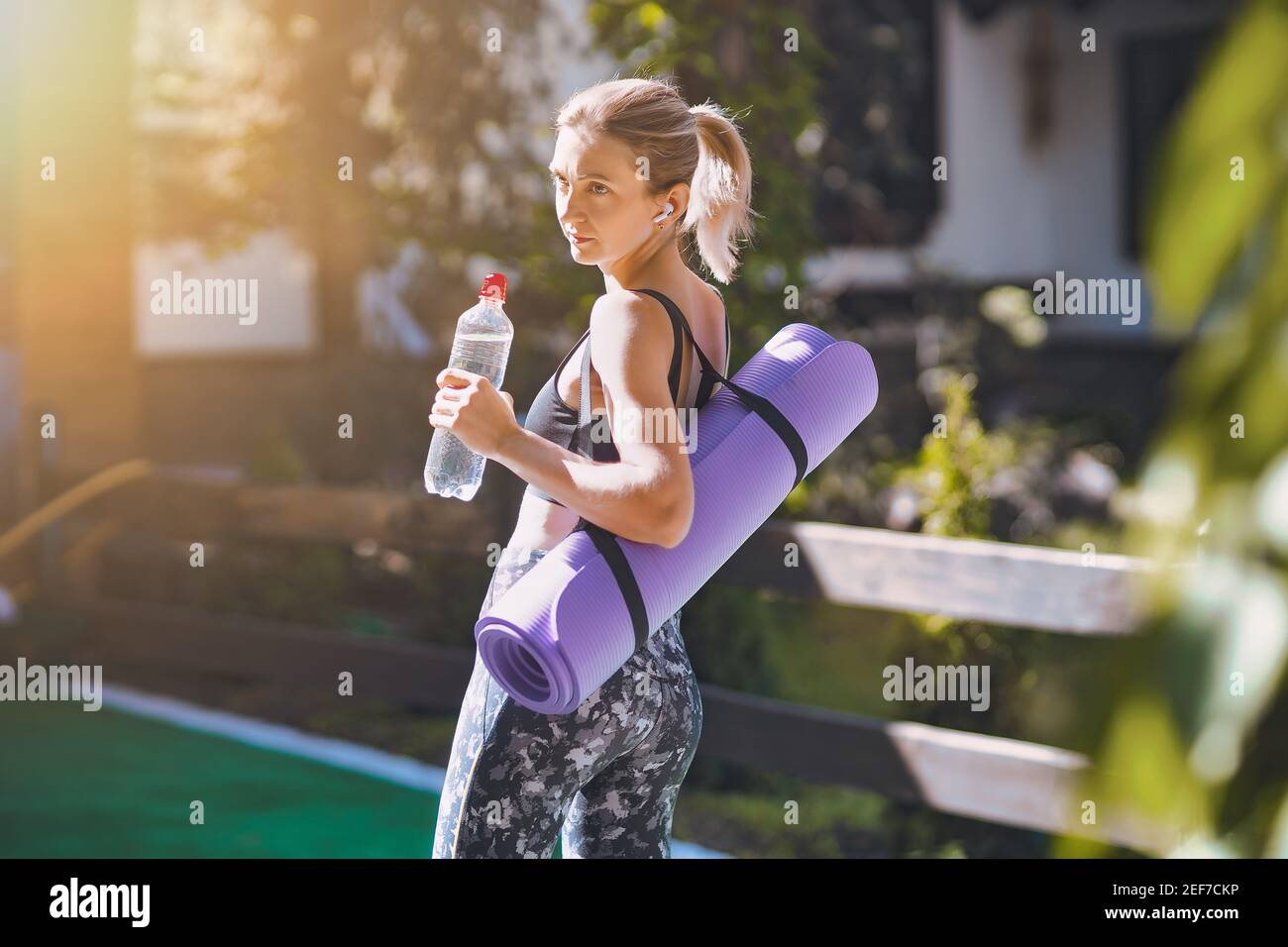https://c8.alamy.com/comp/2EF7CKP/woman-in-sport-clothes-holding-a-yoga-mat-and-water-bottle-after-workout-2EF7CKP.jpg