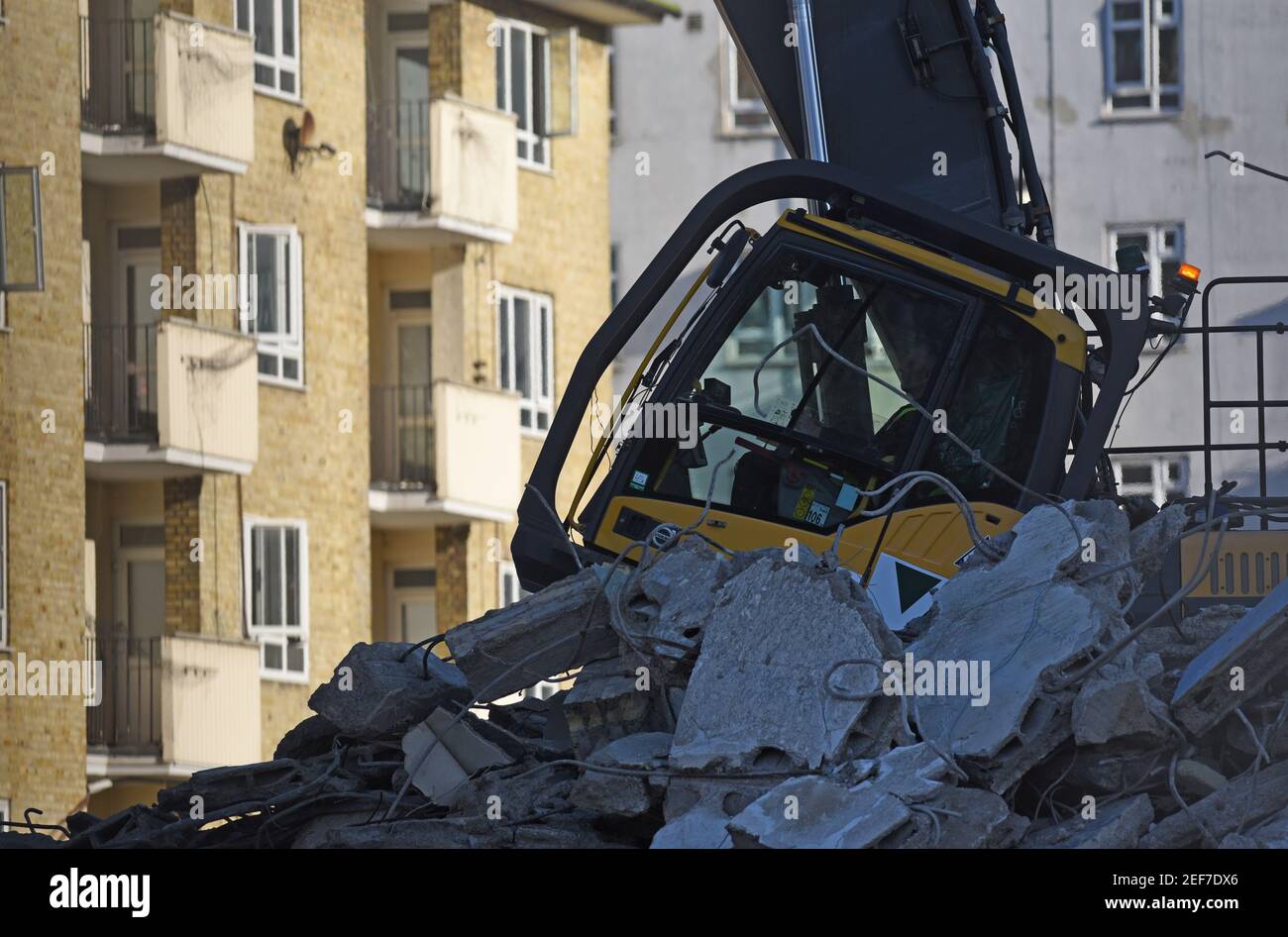 Urban regeneration. An operator uses a Volvo EC380EHR high reach excavator to demolish brick built apartment buildings. Stock Photo