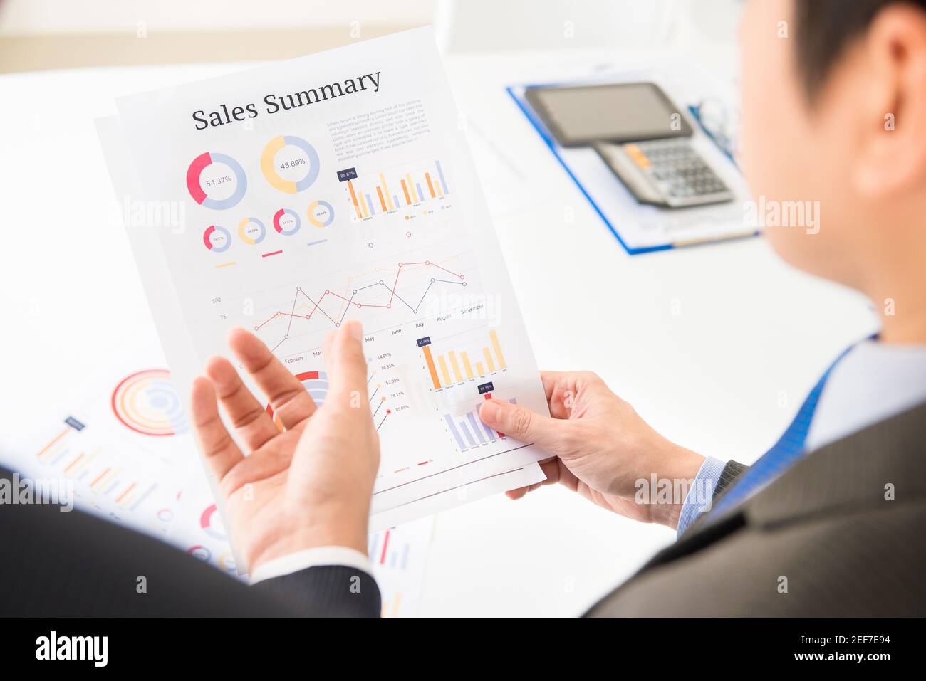 Businessmen discussing and analyzing Sales Summary documents Stock Photo