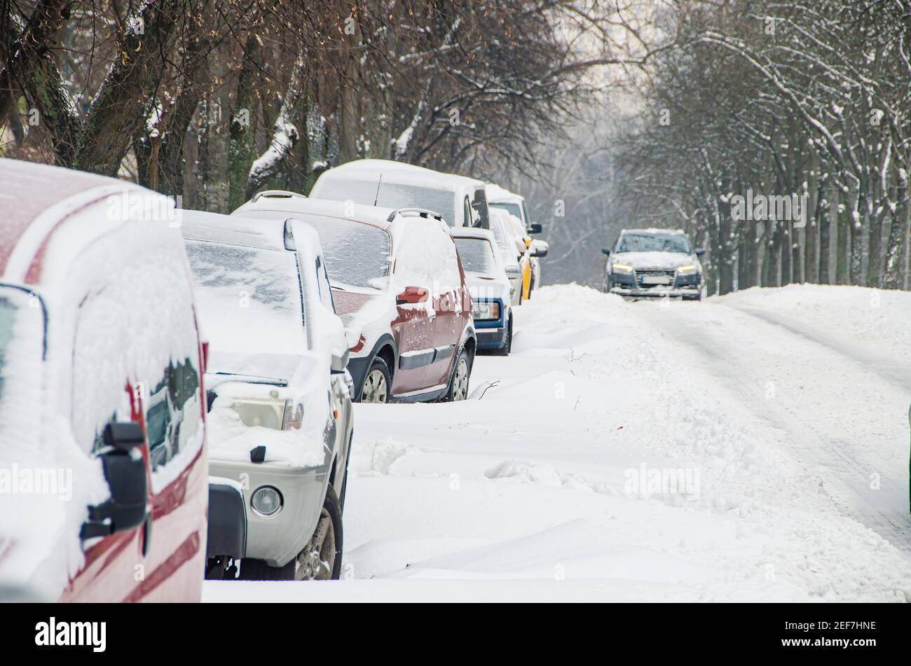 Slippery road covered by snow and cars parked in the snowdrifts. Bad