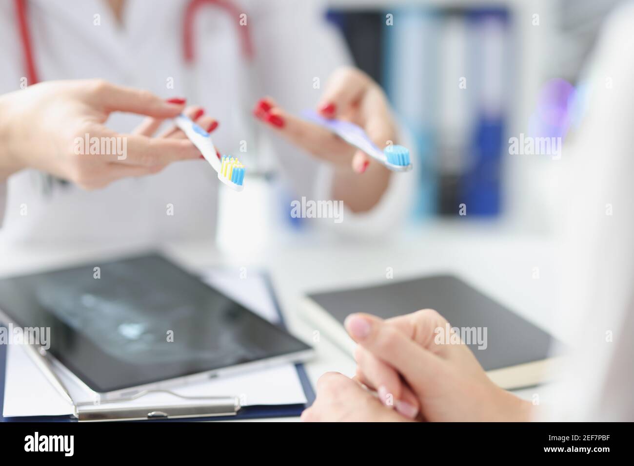 Dentist shows two toothbrushes to patient closeup Stock Photo Alamy