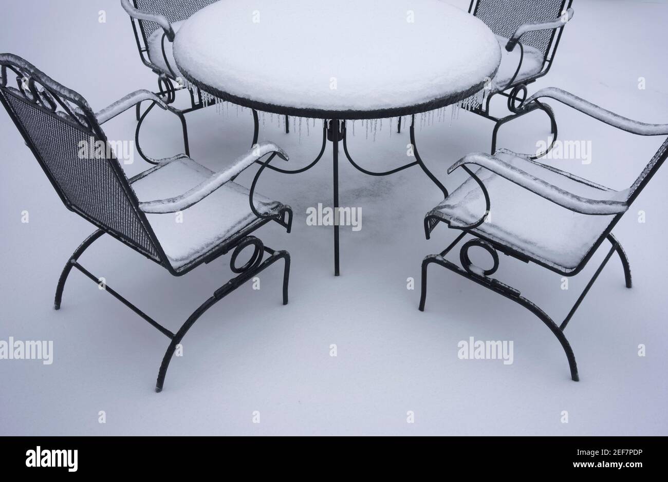 Frozen and snow covered outdoor patio table and chairs after snow