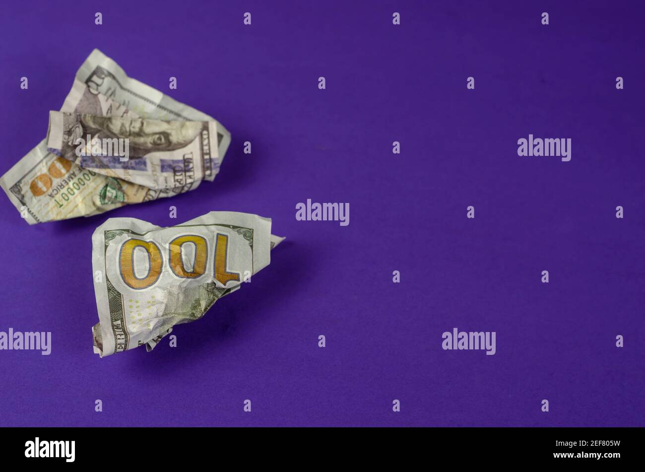Rumpled money lies on a blue background. Two crumpled hundred dollar bills. Side view from an angle. Selective focus. Copy space. Stock Photo