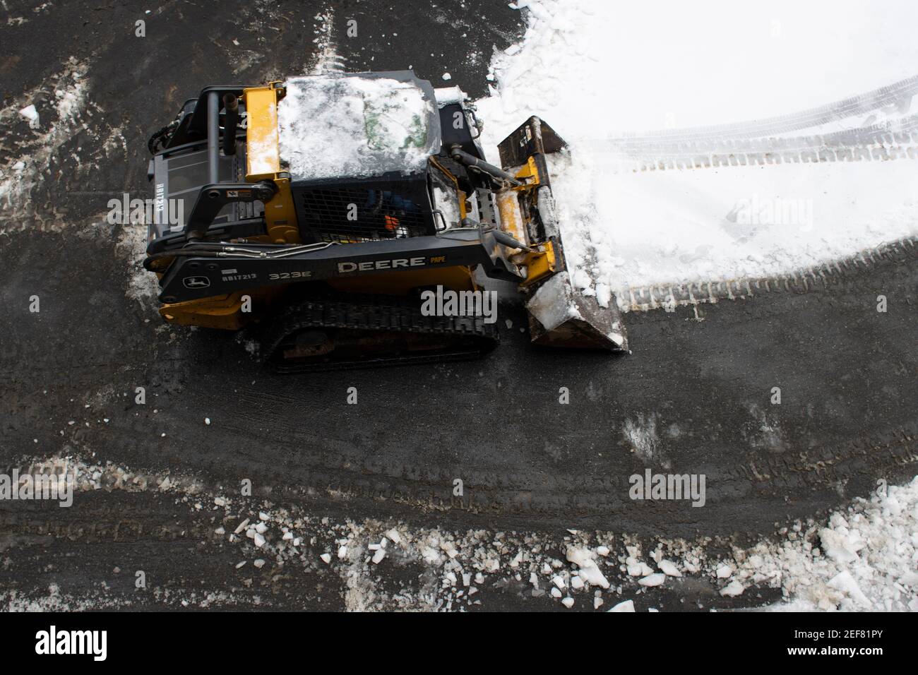 A worker operates a John Deere 323E compact track loader to perform de-icing tasks in a neighborhood in Lake Oswego, Ore., after snow and freezing rain. Stock Photo