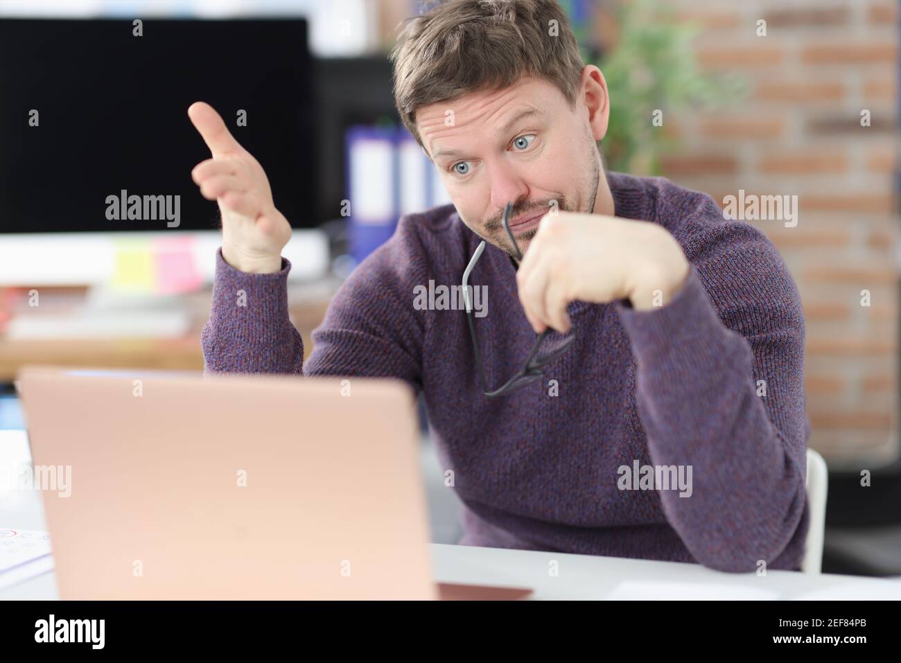 Surprised man looks at laptop screen in office Stock Photo
