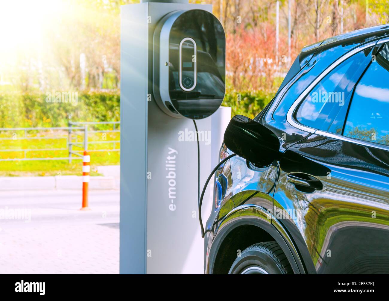 Refueling for cars e-mobility. Charging an electric car at hybrid engine gasoline and electricity. Sunlight as an electric renewable energy concept Stock Photo