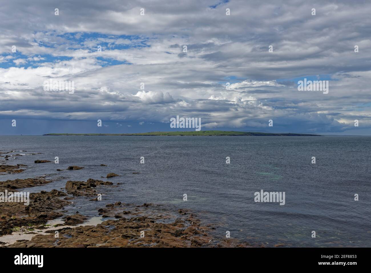 Looking across to the the island of Stroma, part of the Orkneys from the rocky beach at John OÕGroats on a fine late afternoon in May. Stock Photo