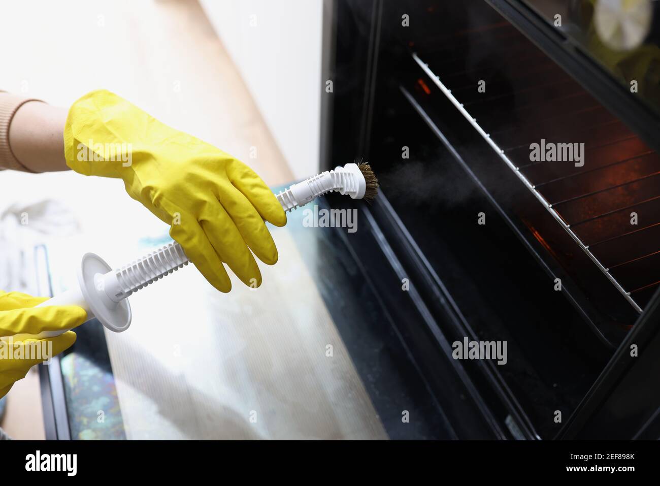 https://c8.alamy.com/comp/2EF898K/female-hands-in-yellow-gloves-are-holding-a-steam-cleaner-and-cleaning-oven-2EF898K.jpg