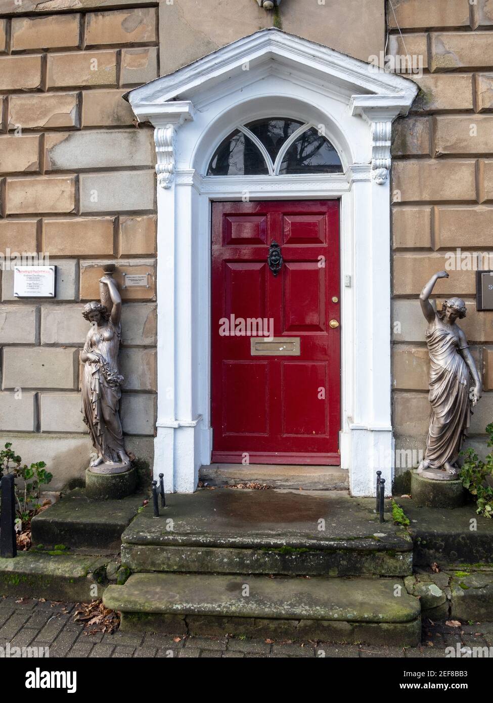 Ornate front door, flanked by two classical statues, of a