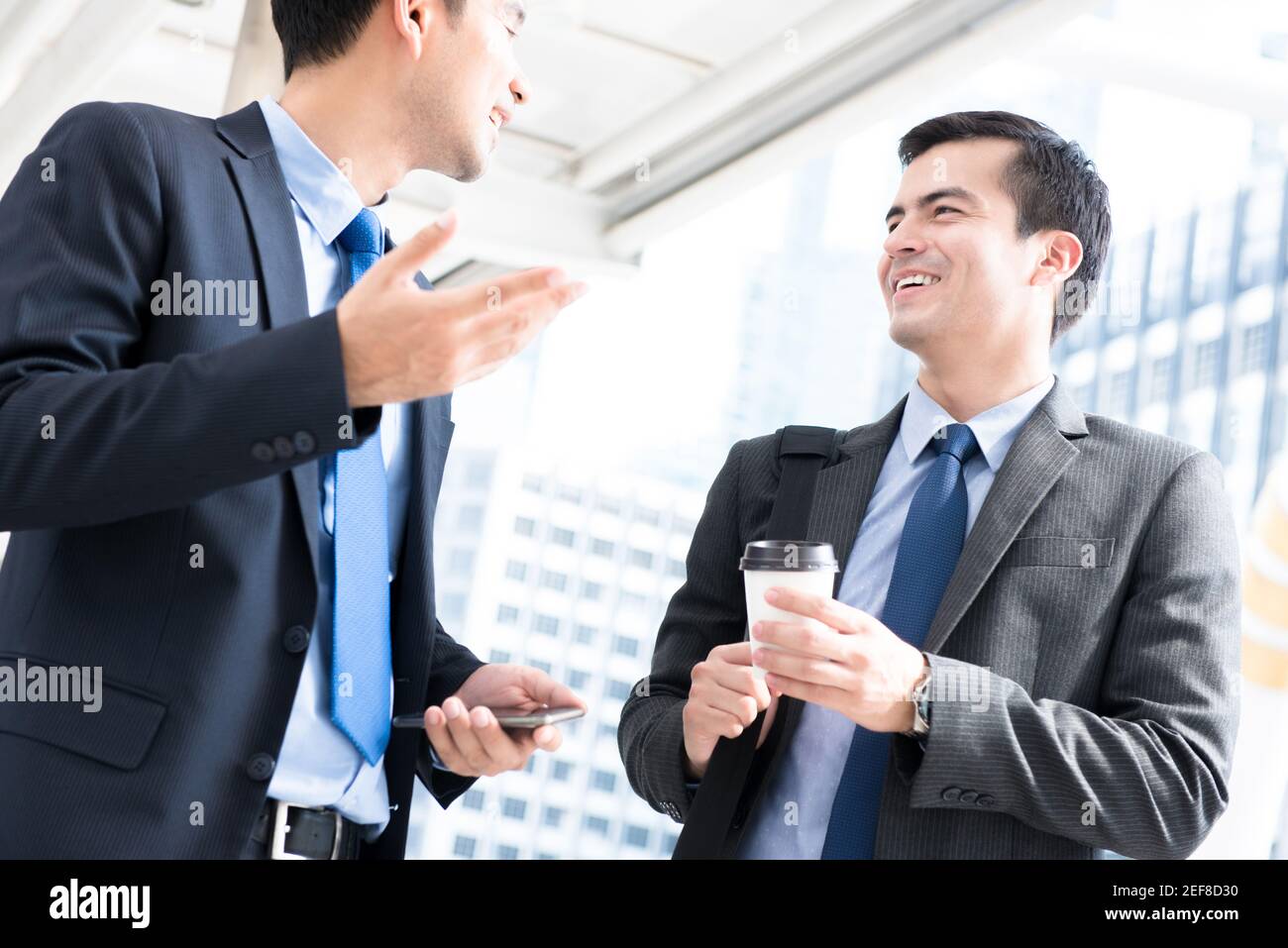 Businessmen greeting and talking while walking to work in the morning at outdoor covered walkway Stock Photo