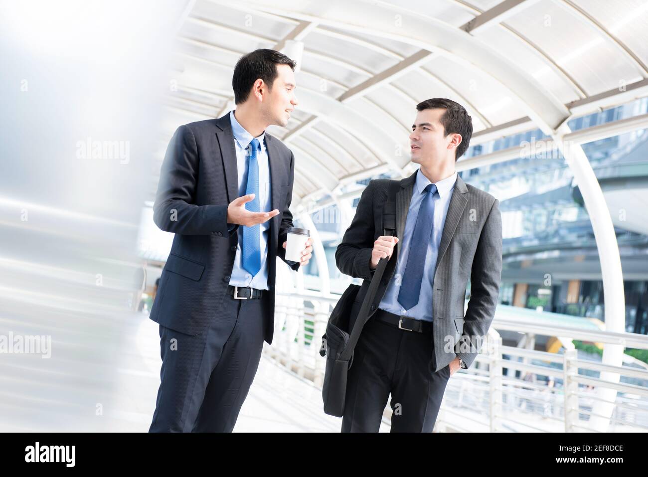 Interracial businessmen as colleague, walking and talking in the morning at outdoor covered walkway Stock Photo