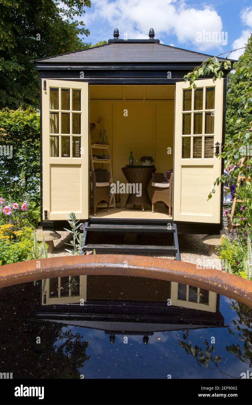 A small English cottage garden with Summerhouse Shepherds Hut - working from home office cabin - water feature pond - London UK - posh garden shed Stock Photo