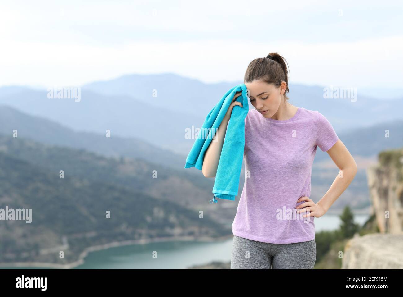 Tired runner drying sweat after sport walking in the mountain Stock Photo
