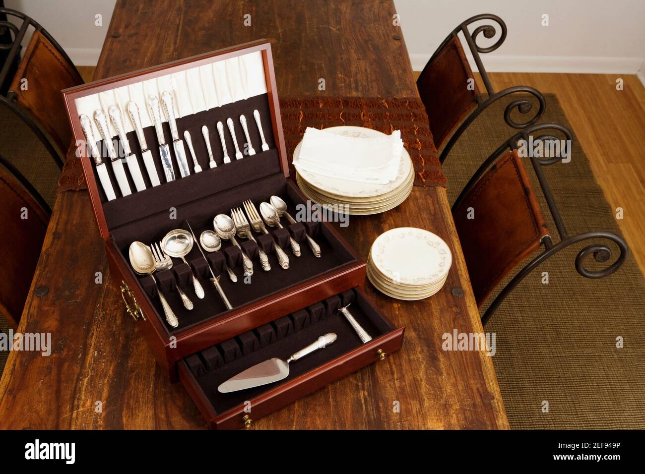 High angle view of an open cutlery box with stacks of plates on a dining table Stock Photo