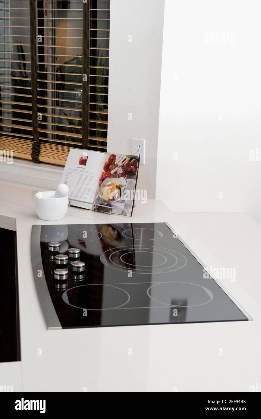 Mortar and a pestle with a cookbook on a kitchen counter Stock Photo