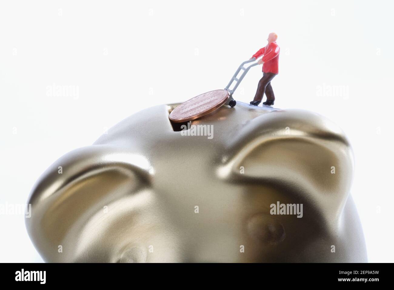 Figurine of a man putting a coin into a piggy bank Stock Photo - Alamy