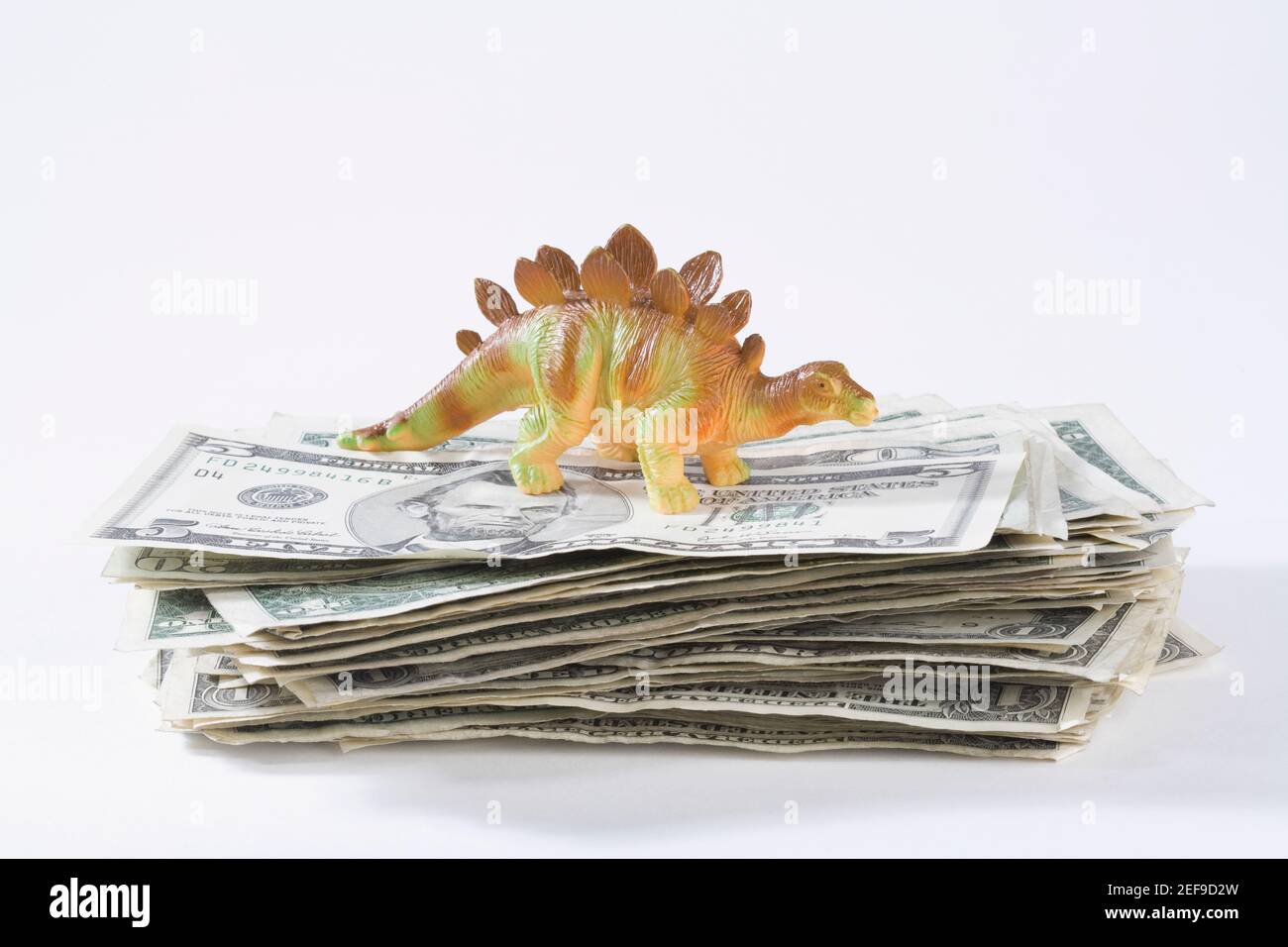 Close up of a figurine of a dinosaur on a stack of US paper currency Stock Photo