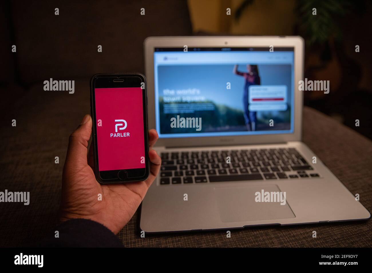 Parler app on the iPhone display standing in front of a macbook.  Parler is a new social networking service very popular during the US elections Stock Photo