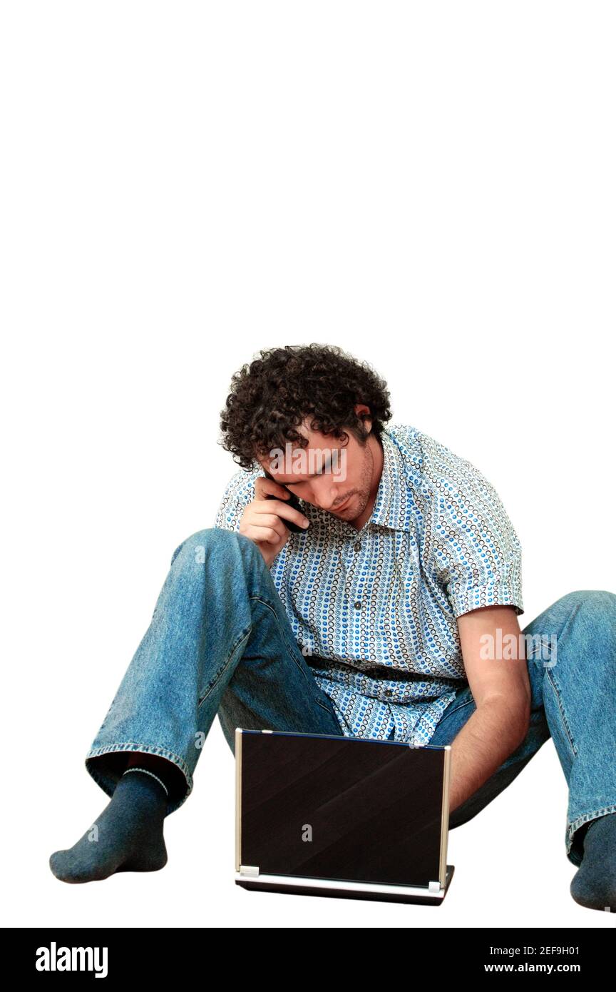 Young man talking on a mobile phone and using a laptop Stock Photo