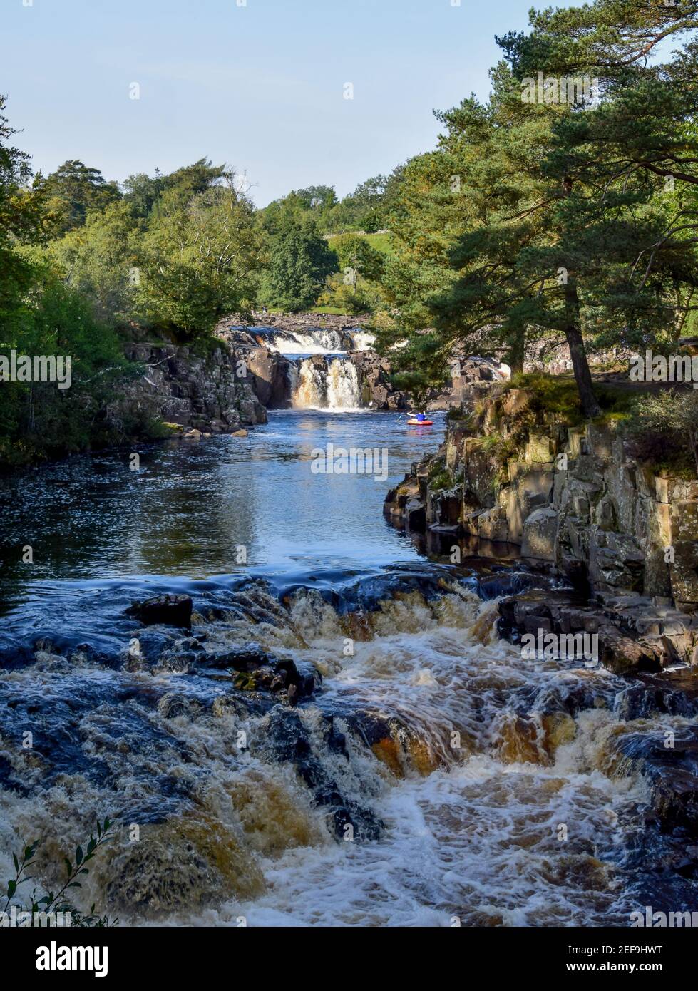 Low force Waterfall on a sunny day with Kayakers enjoying the river and its force Stock Photo