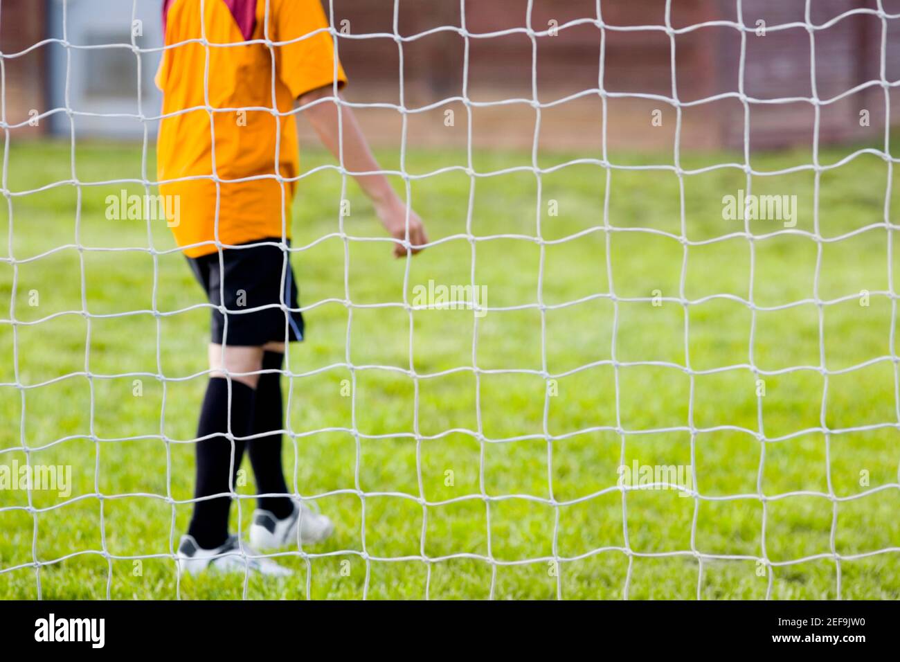 Side profile of a soccer player standing behind a net Stock Photo