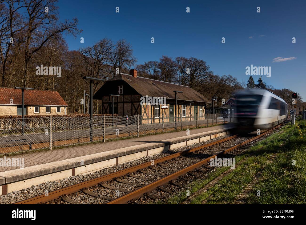 A local commuter train passing an old station in Odense Denmark Stock Photo