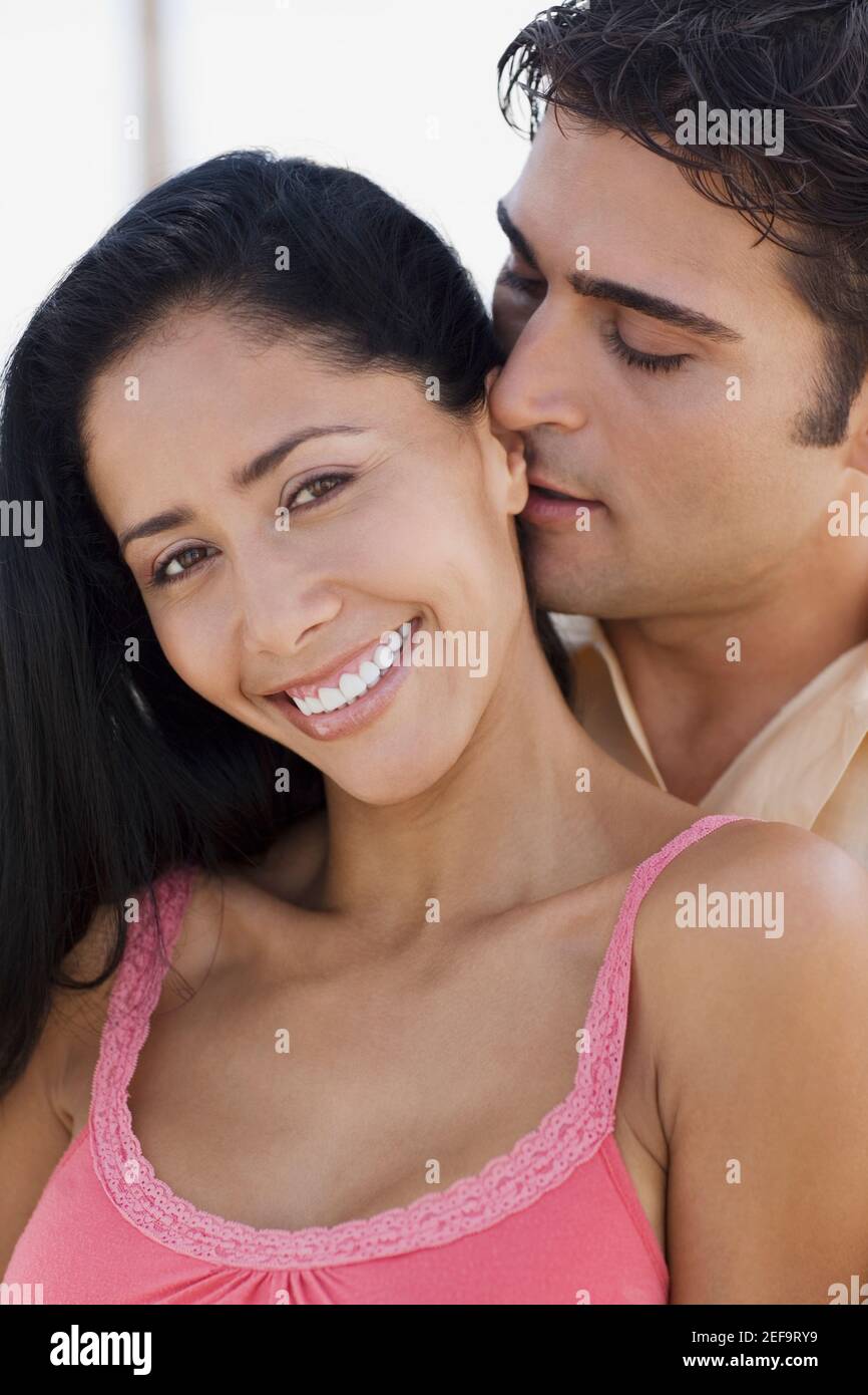 Close-up of a young man embracing a young woman from behind Stock Photo ...