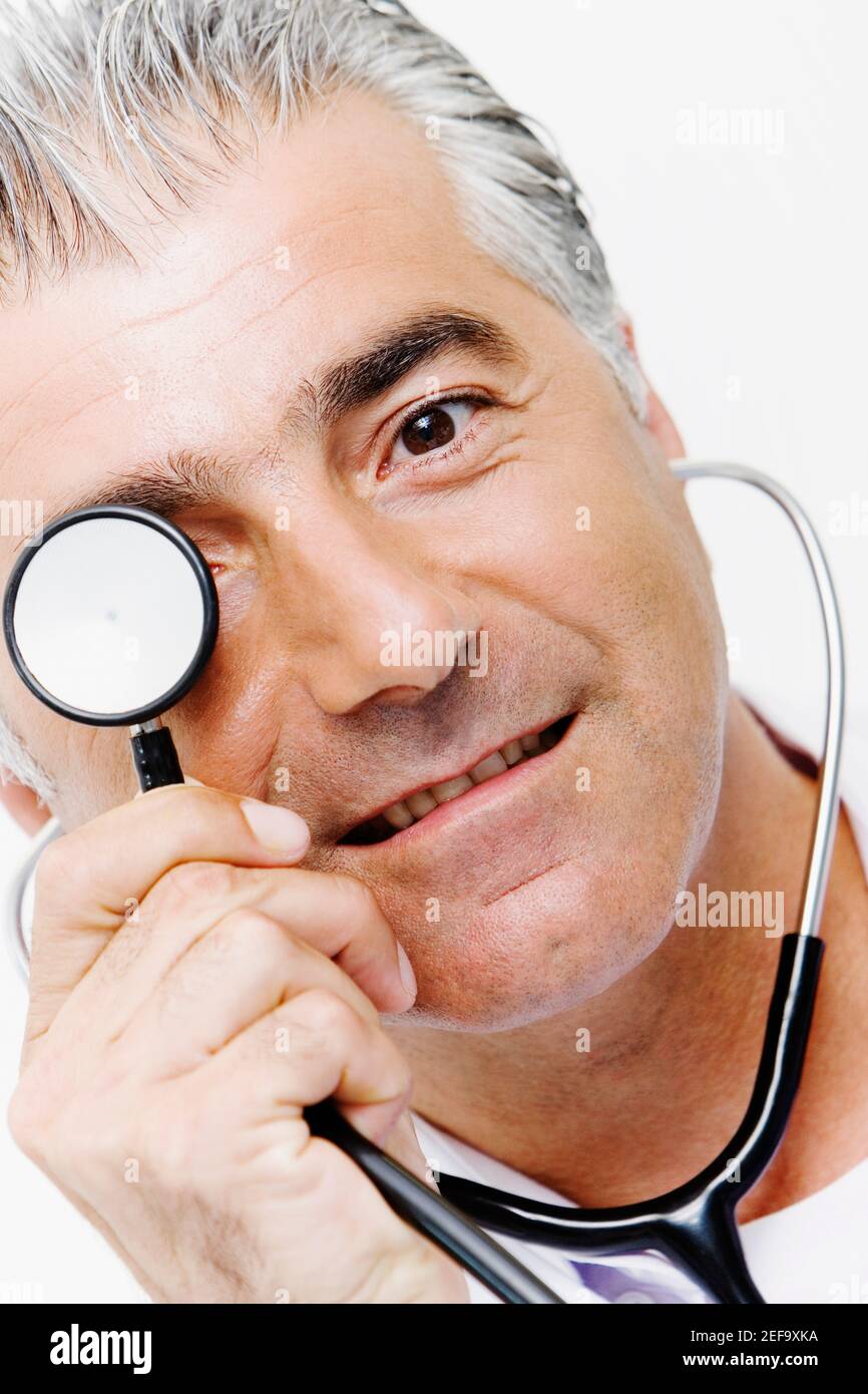 Portrait of a male doctor holding a stethoscope in front of his eyes ...