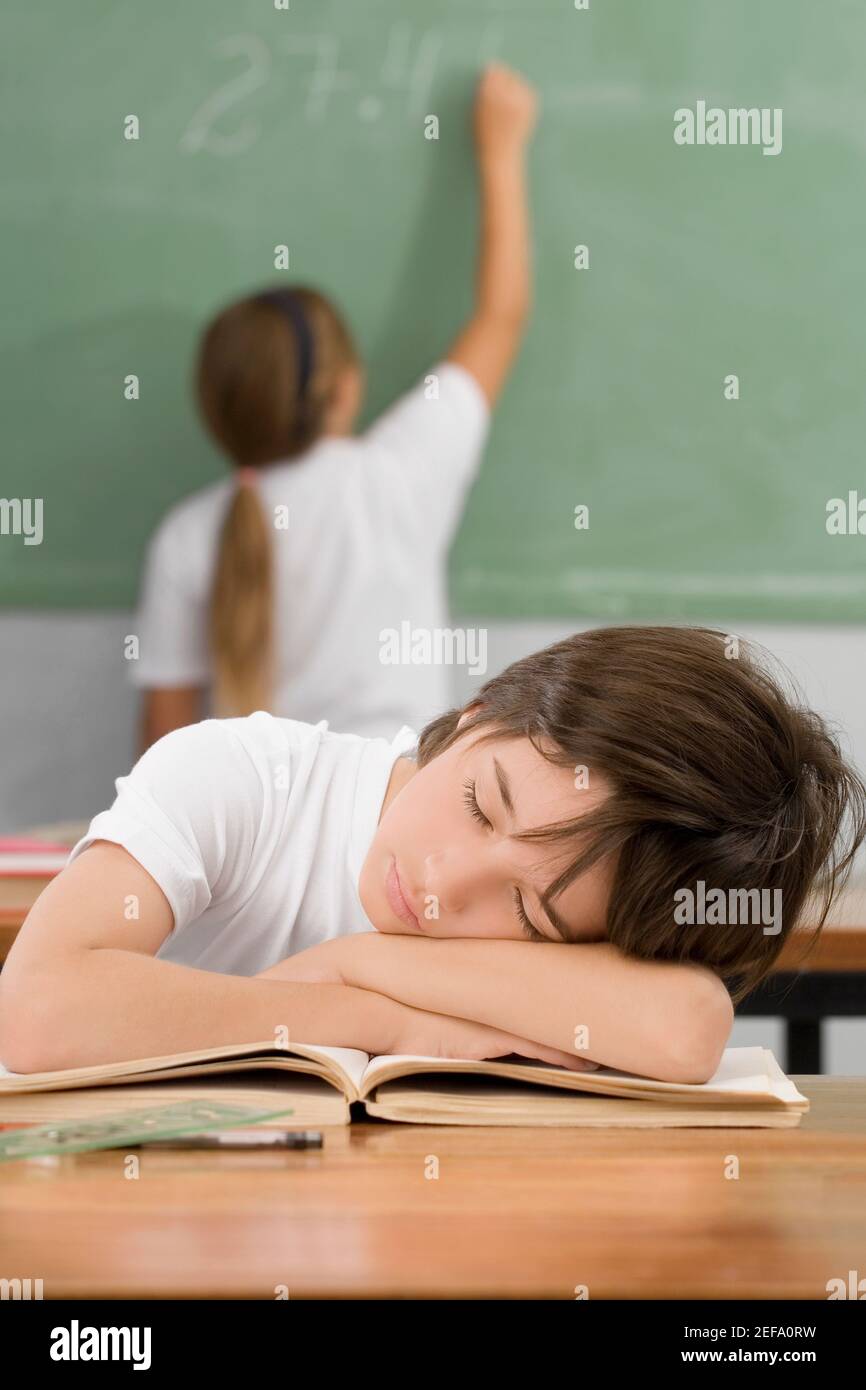Schoolboy napping on a desk in a classroom Stock Photo