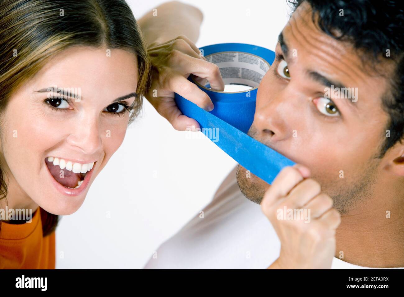 Portrait of a mid adult woman sticking an adhesive tape on a young manÅ½s mouth Stock Photo