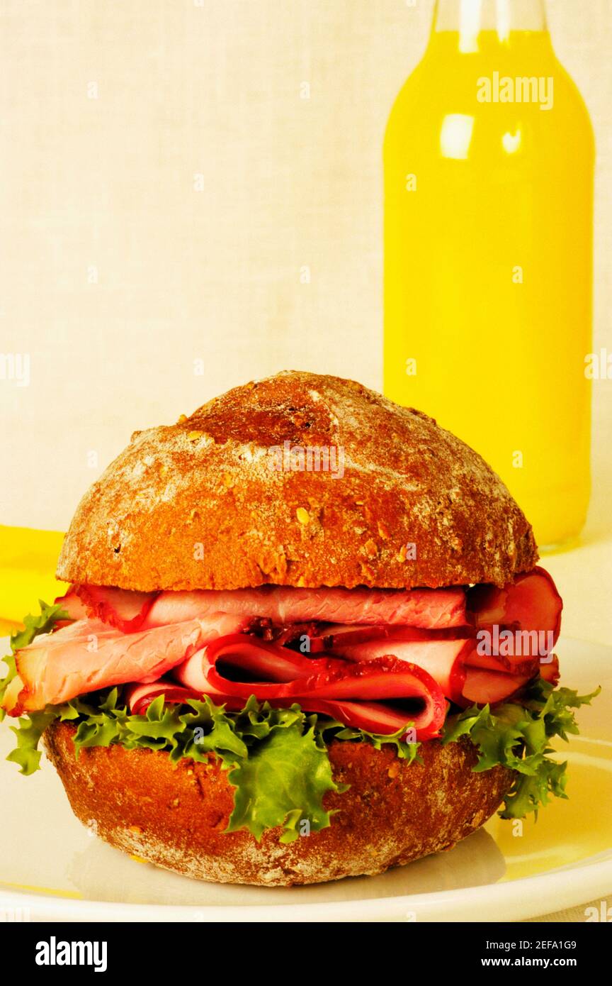 Closeup of a roast beef burger and a bottle of orange juice Stock