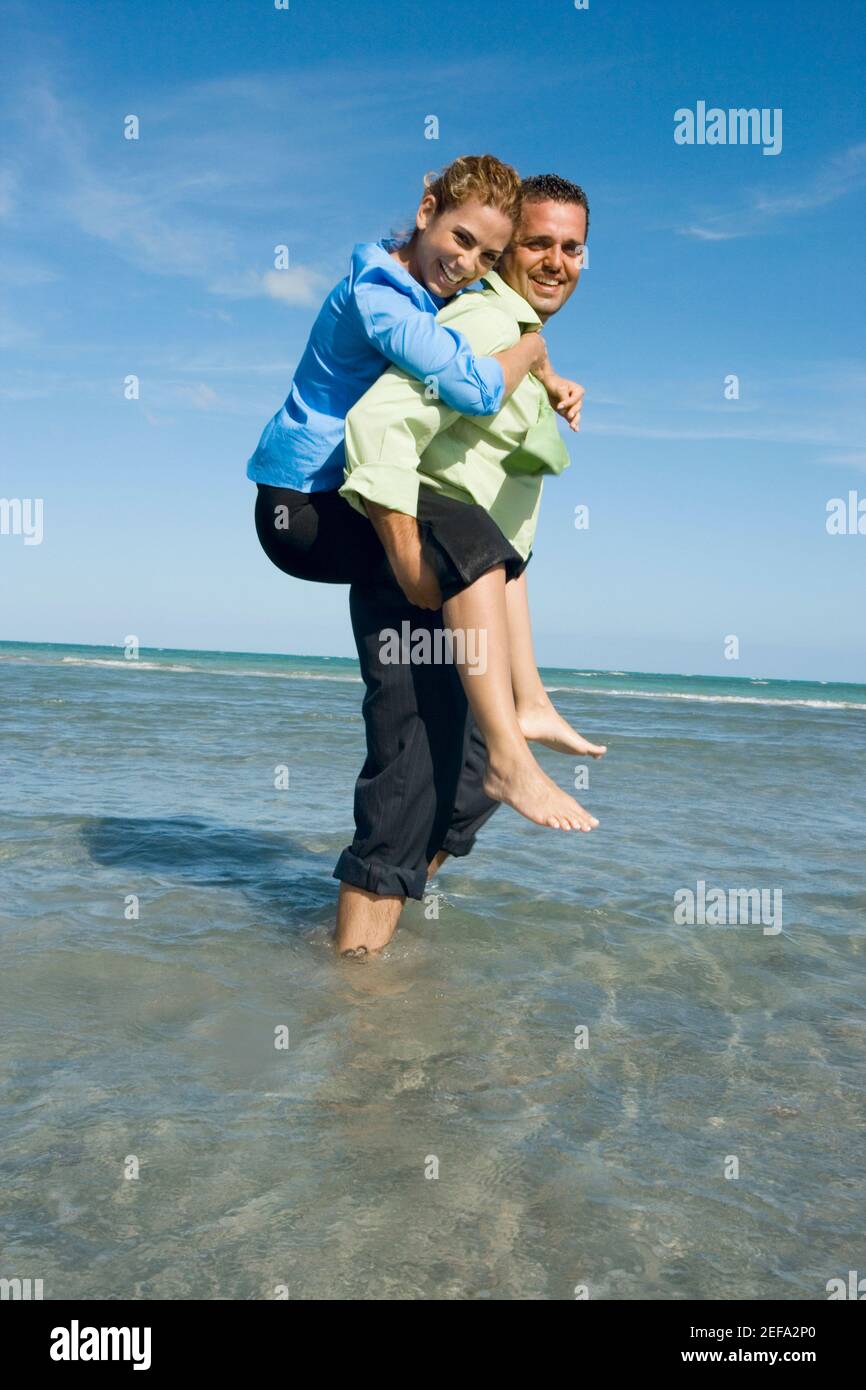 Side profile of a mid adult woman riding piggyback on a mid adult man ...