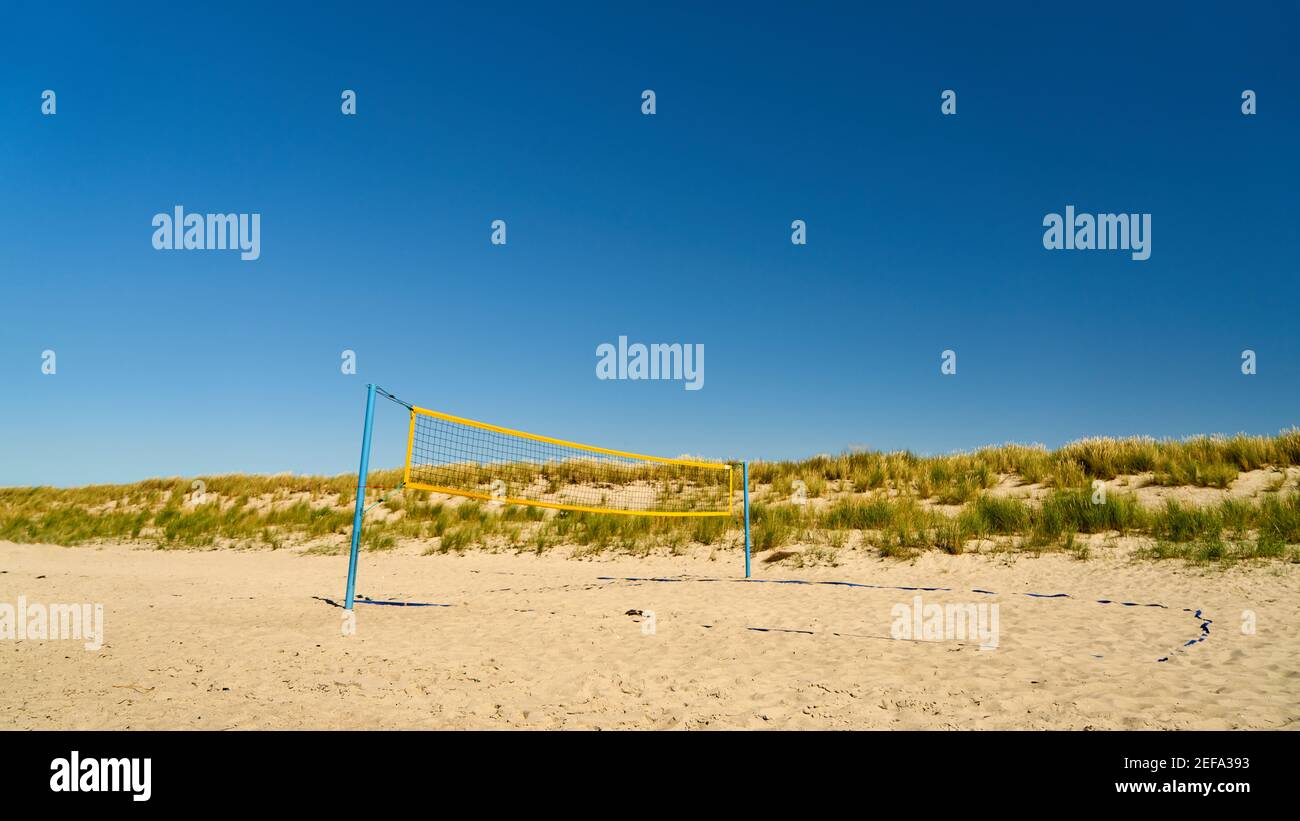 Playing field with net for beach volleyball on the sandy beach against a blue sky in summer Stock Photo