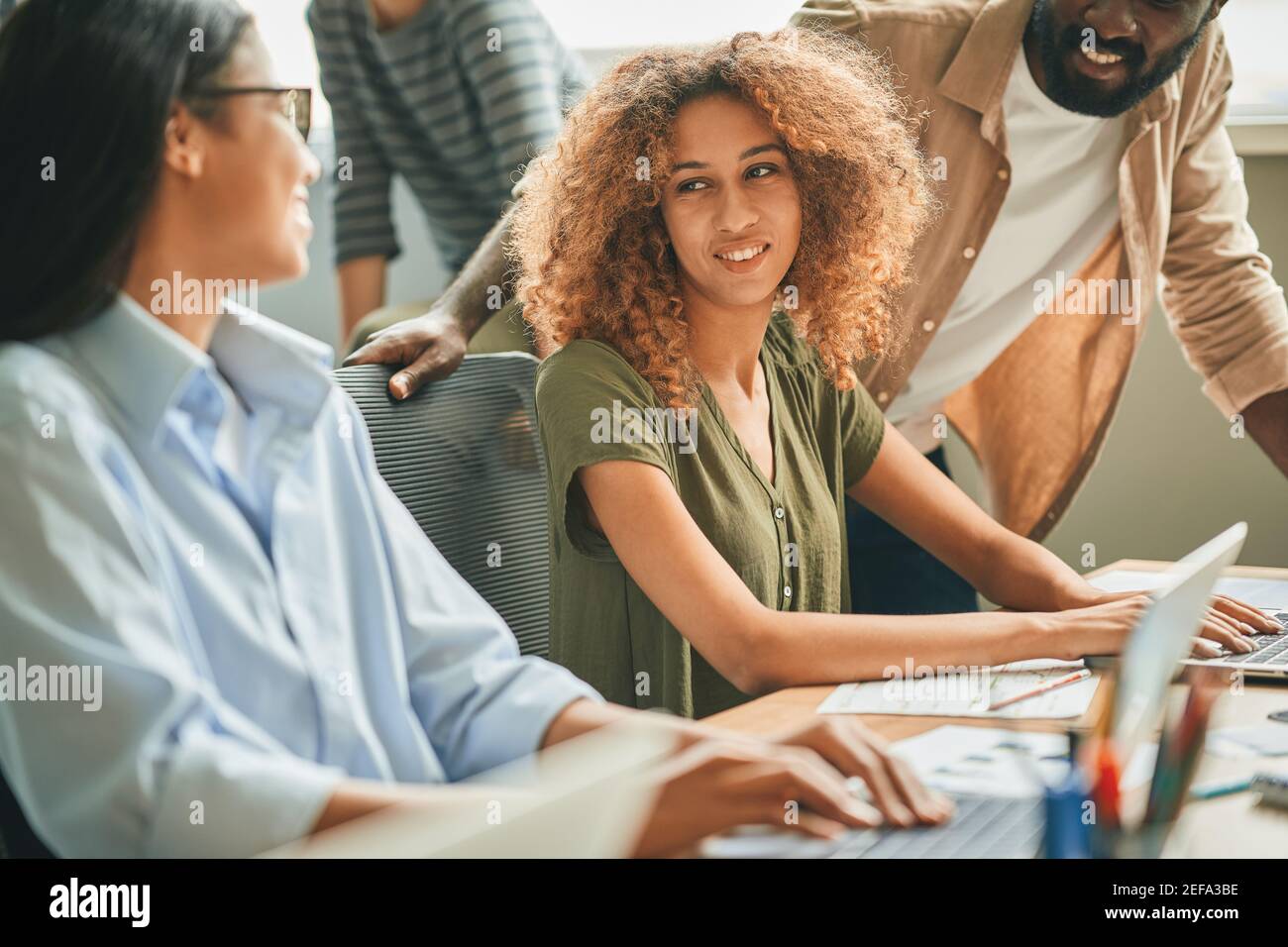 Three multiracial young people having a work-related conversation Stock Photo