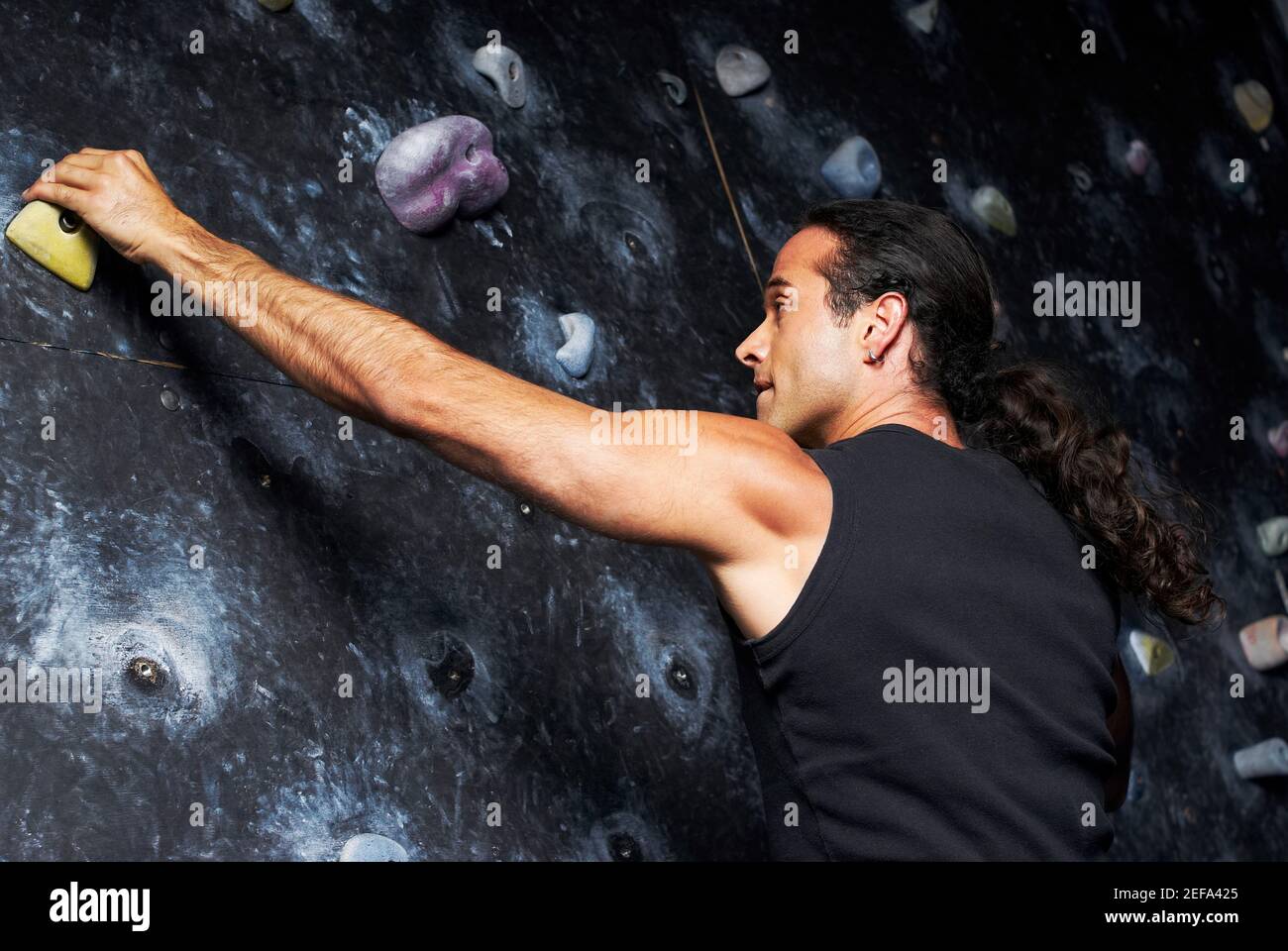 Rear view of a mid adult man climbing a wall Stock Photo