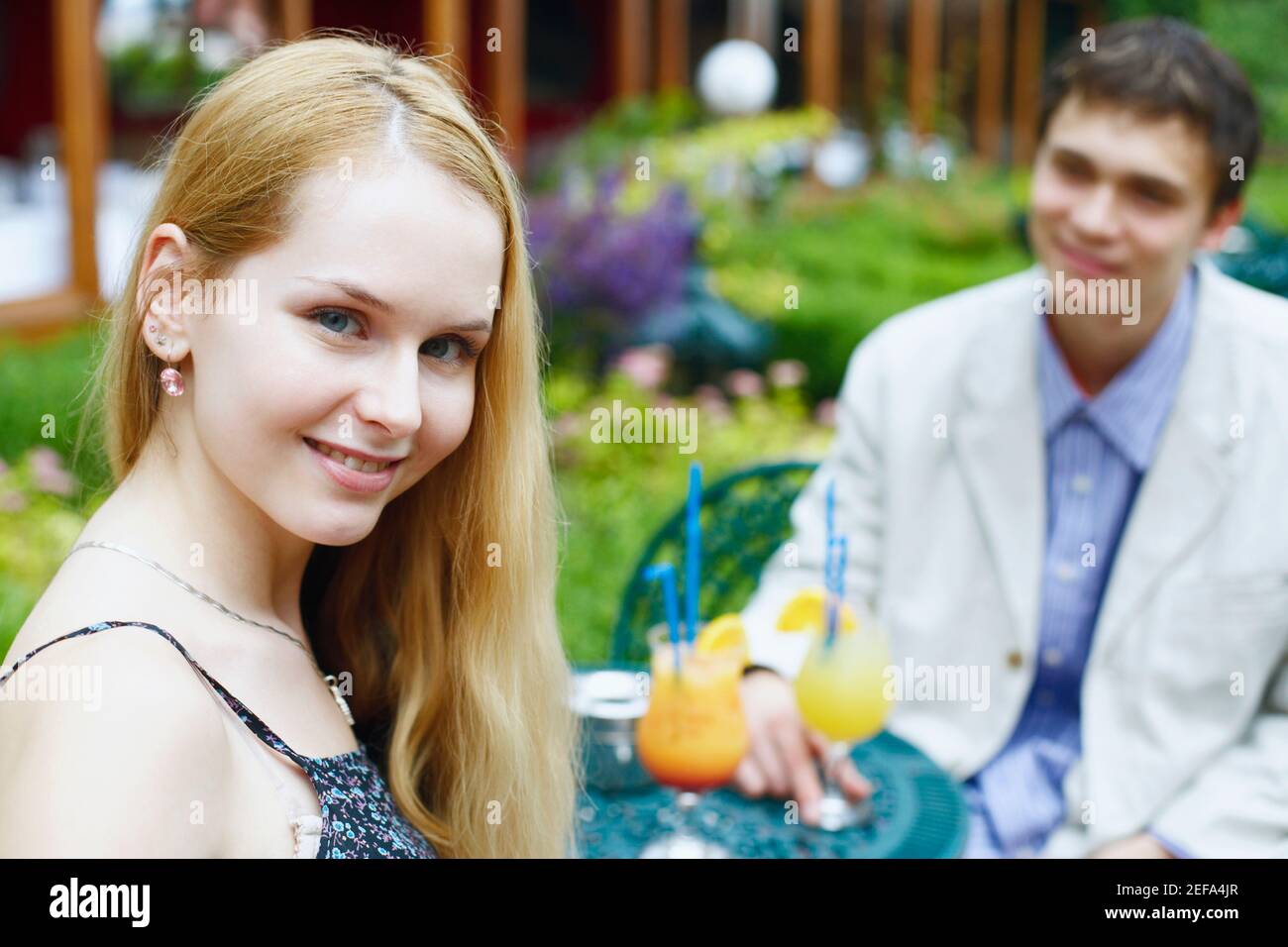 Portrait of a young woman smiling with a young man sitting with her Stock Photo