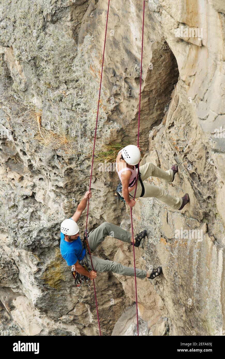 High angle view of a male and a female rock climber scaling a rock face
