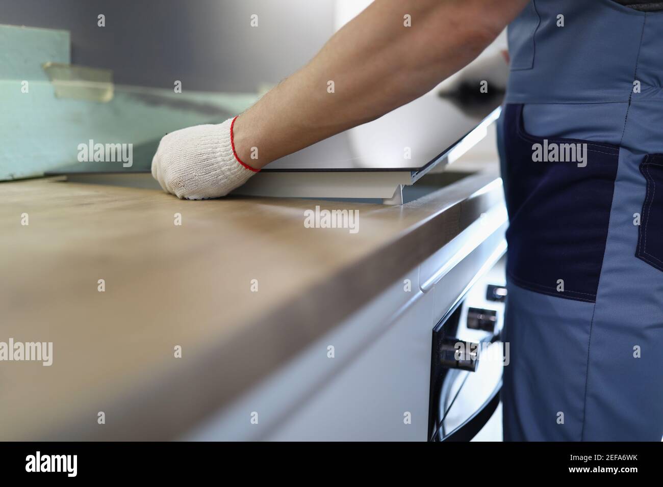 Gloved craftsman installs hob in kitchen closeup Stock Photo