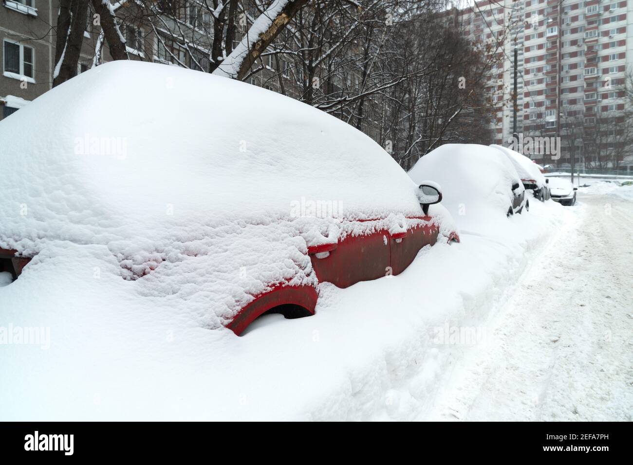 Cars covered with snow after a hard blizzard on the roadside of a ...