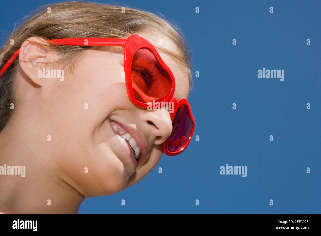 Low angle view of a girl wearing red sunglasses and smiling Stock Photo