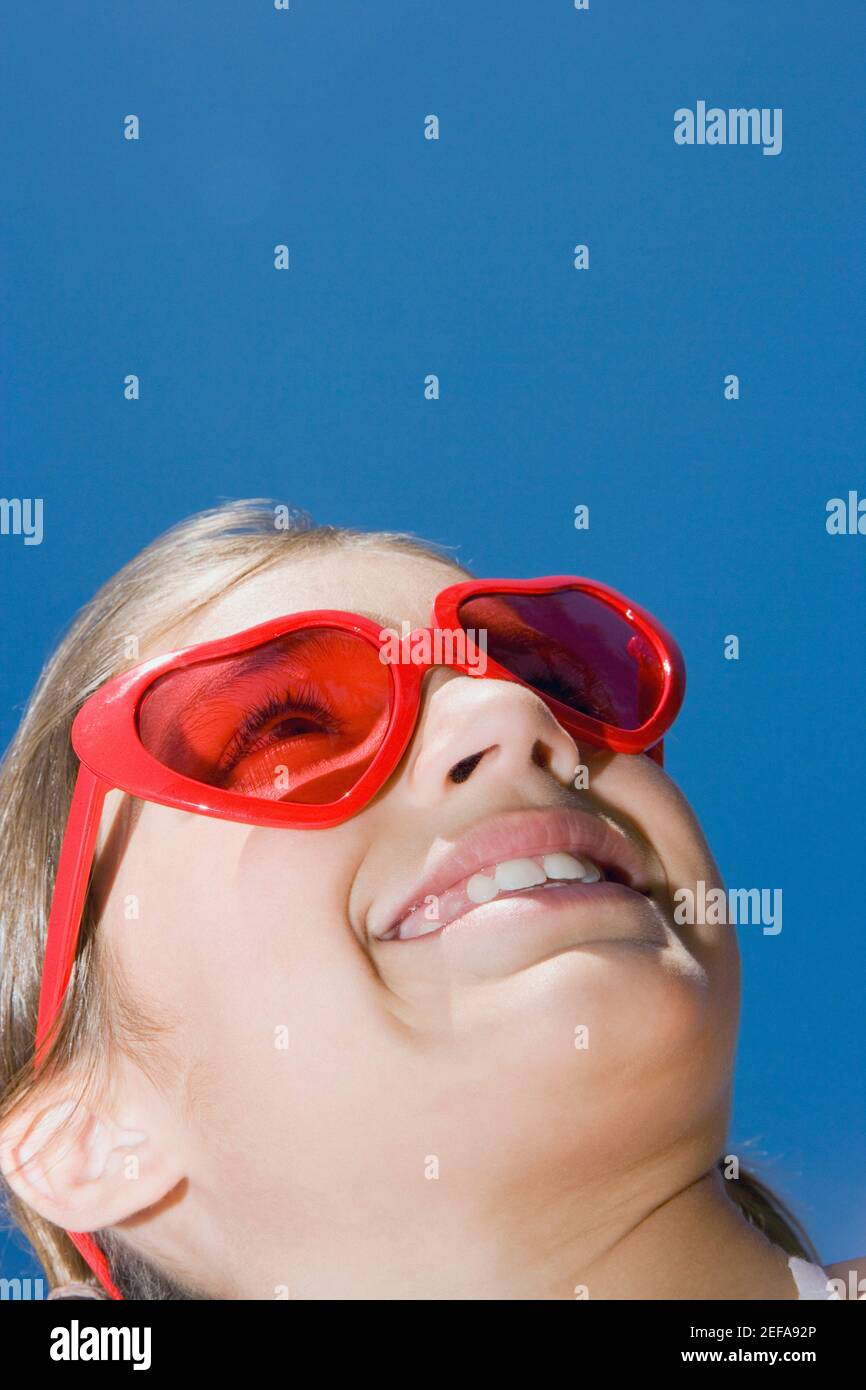 Low angle view of a girl wearing red sunglasses and smiling Stock Photo