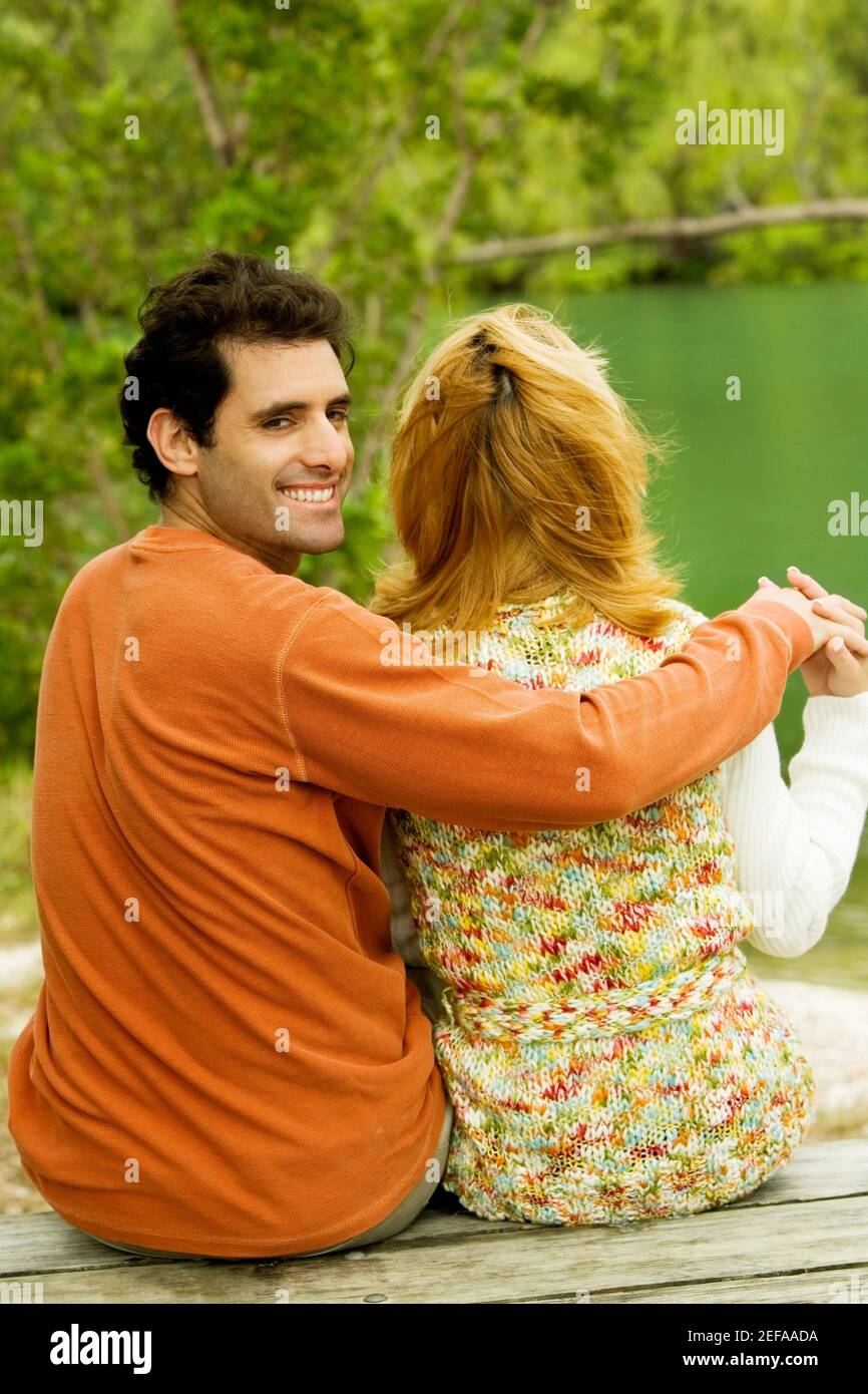 Rear view of a mid adult man sitting with his arm around a young woman ...