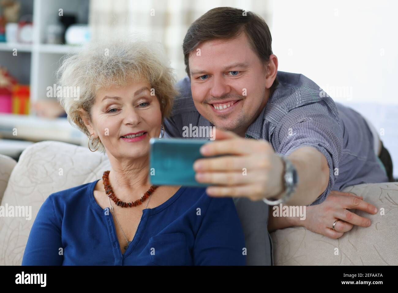 Young man takes selfie on smartphone with his mom Stock Photo