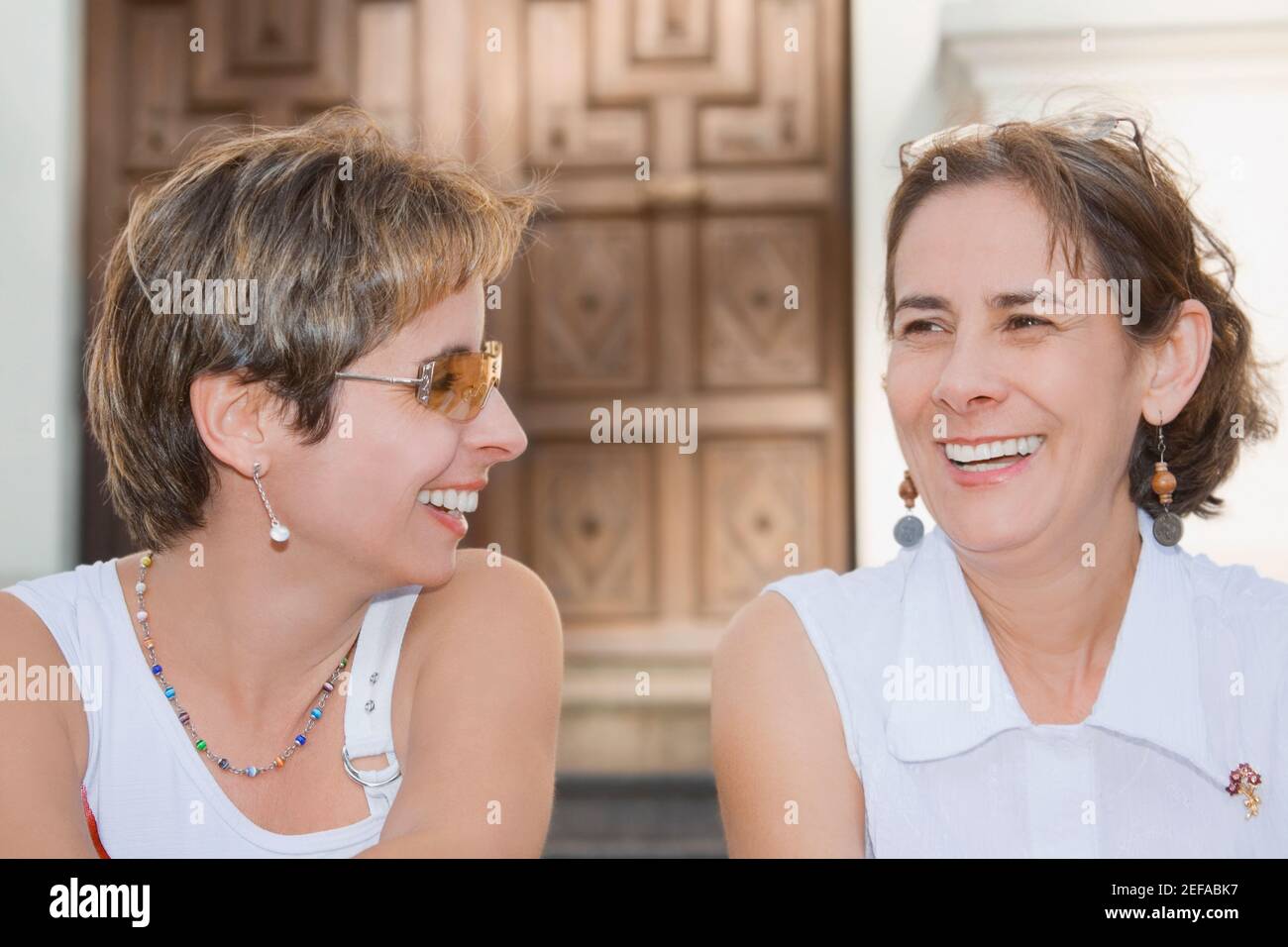Close-up of a mid adult woman sitting with a mature woman and laughing Stock Photo