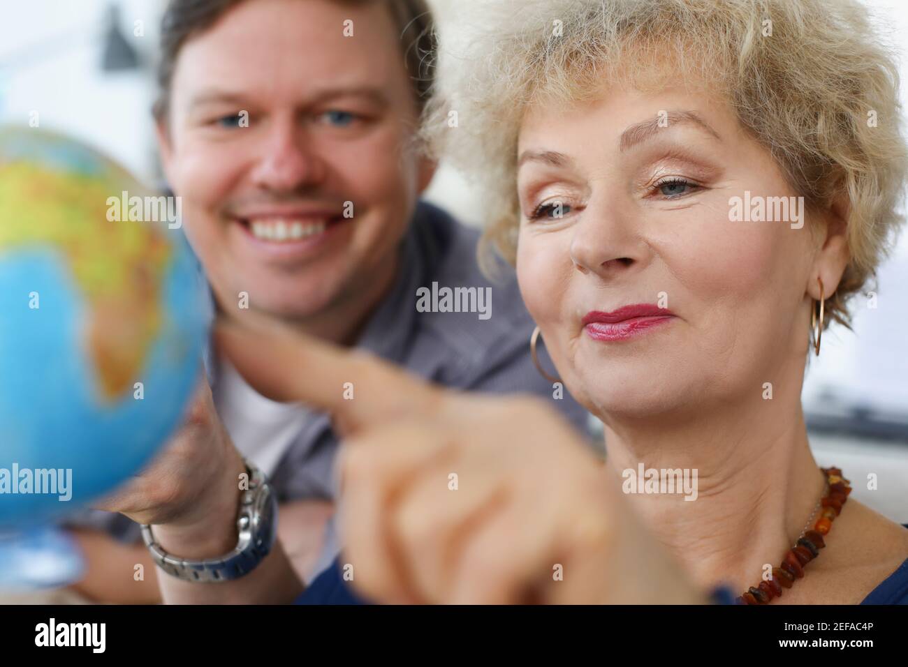 An elderly woman and young man looking at globe Stock Photo