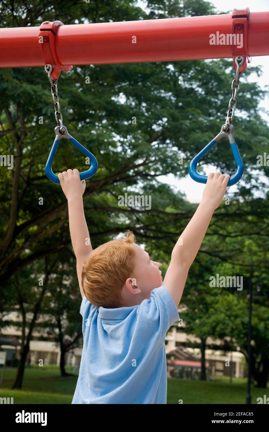 Rear view of a boy hanging on monkey bars Stock Photo