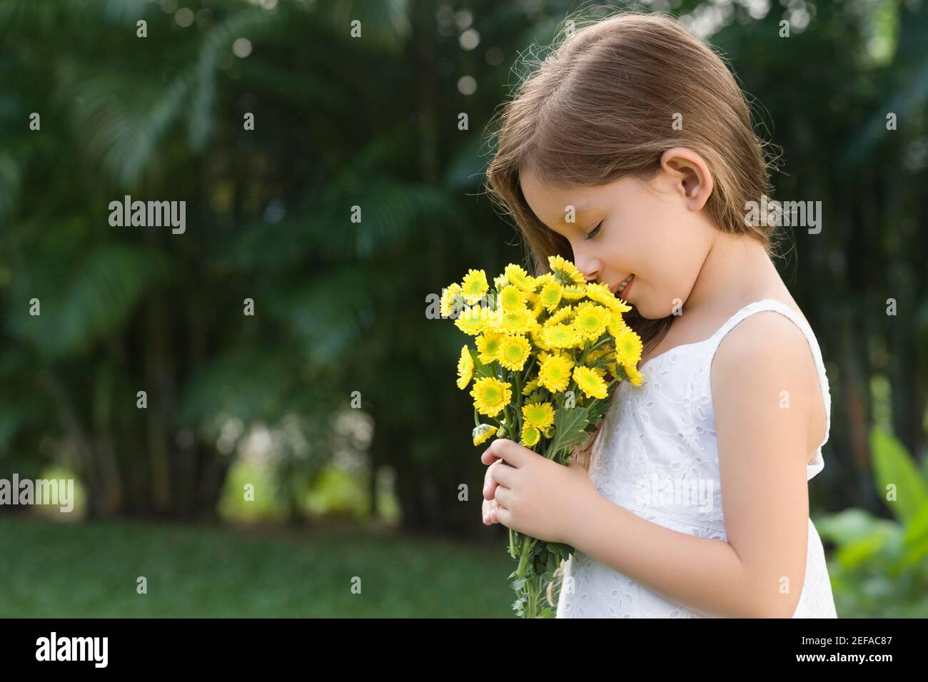 Side profile of a girl holding a bunch of flowers and smelling Stock ...