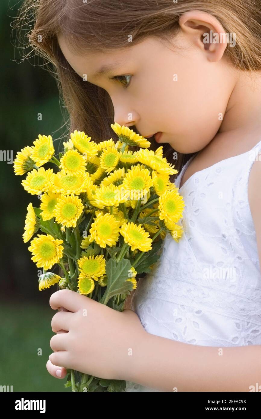 Side profile of a girl holding a bunch of flowers and smelling Stock ...